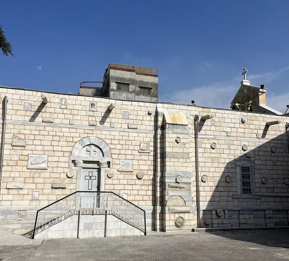 The stone facade and doorway of Saint Porphyrius Church in Gaza City under a blue sky.
